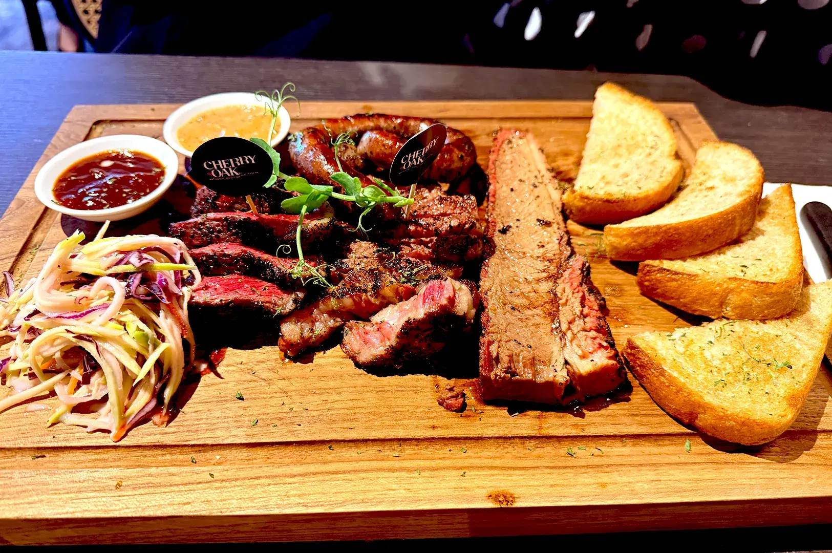 Sumptuous Wagyu Boneless Platter served on a wooden board with sides at Cherry & Oak Steakhouse, an artisanal wood-smoked halal restaurant.