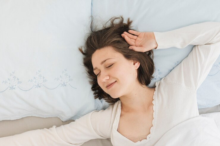 Woman relaxing in bed with hand near her ear