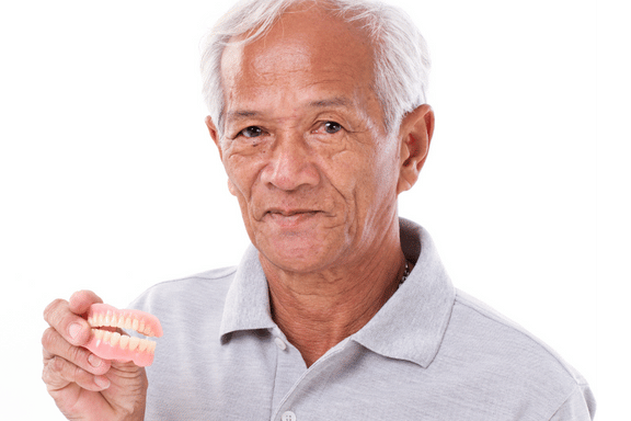 senior male with bone loss holding dental implant dentures