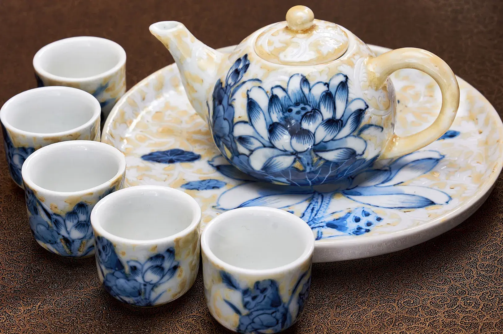 Ceramic teapot and cups with blue hand-painted lotus patterns on a tray.