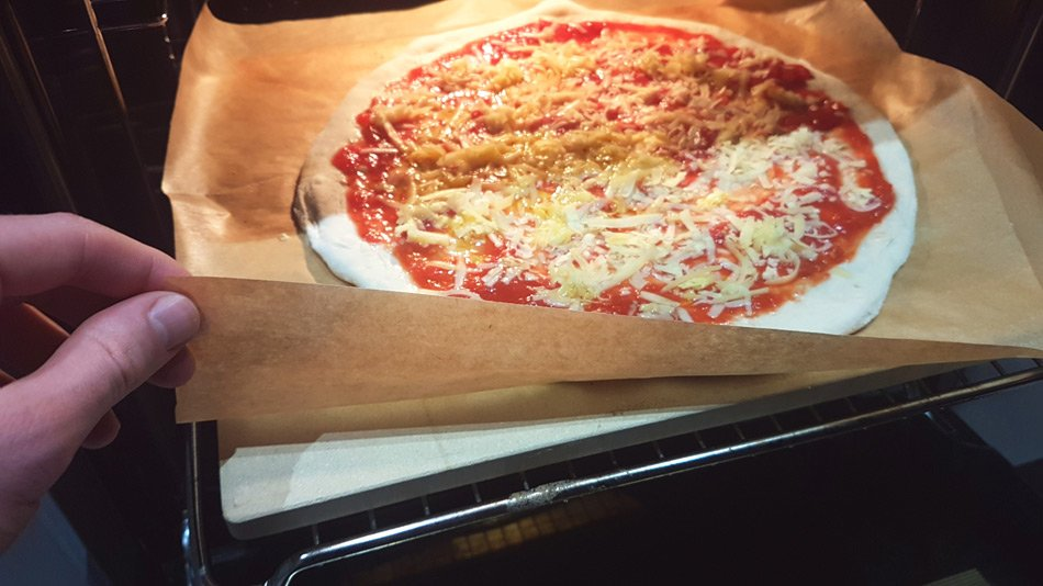 Parchment paper with pizza on a stone