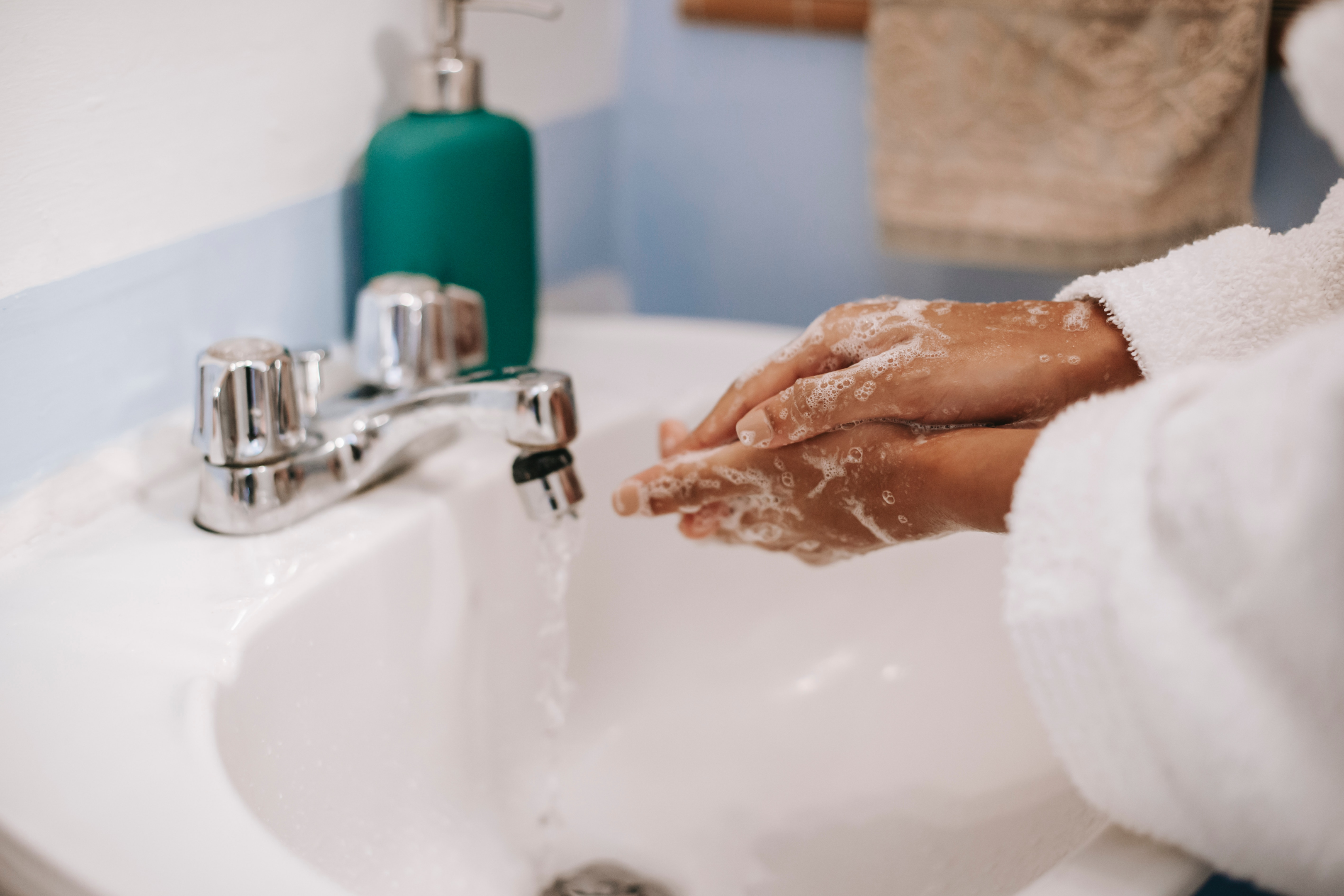 A close-up of a woman washing her hands with soap under running water in a sink.