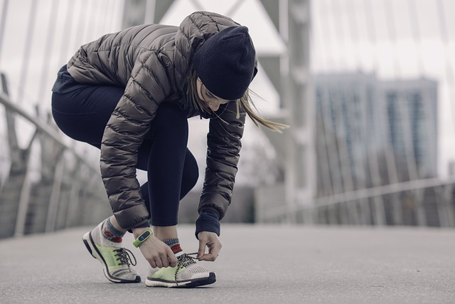 An image of a woman tying her sneakers, working out with sore throat.
