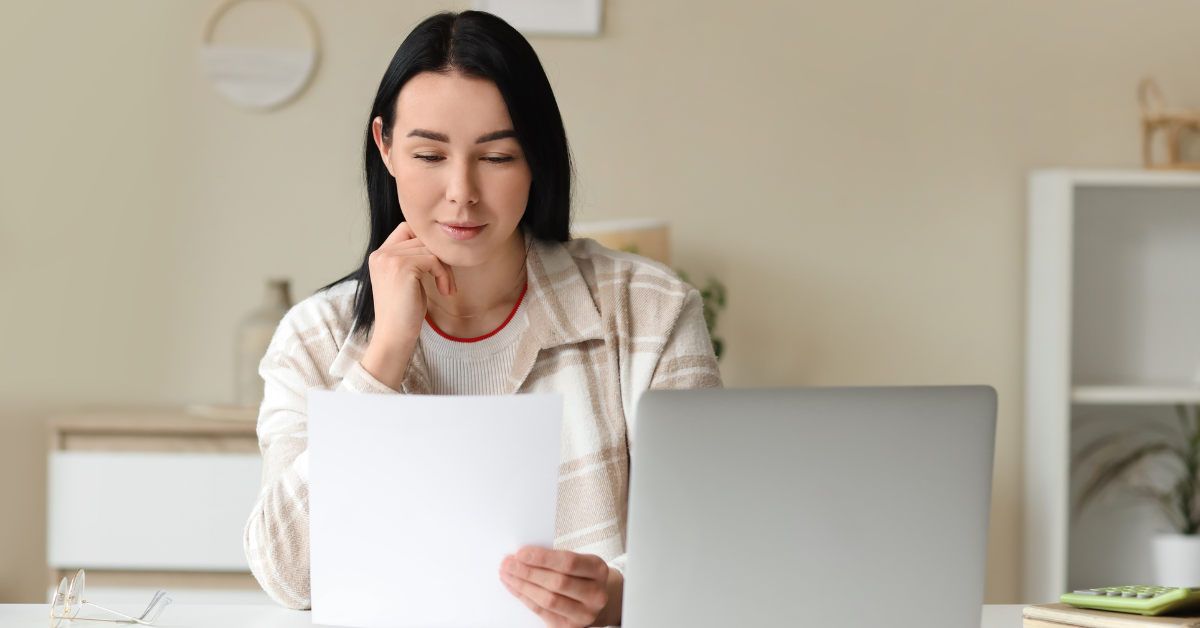 A woman reviewing IRS tax forms and a laptop while researching “how many men are subscribed to OnlyFans in the US” and planning for OnlyFans taxes.