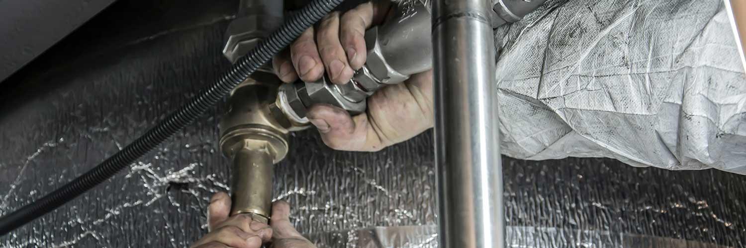 A professional plumber installing a water heater during the rough-in plumbing phase of a new construction project