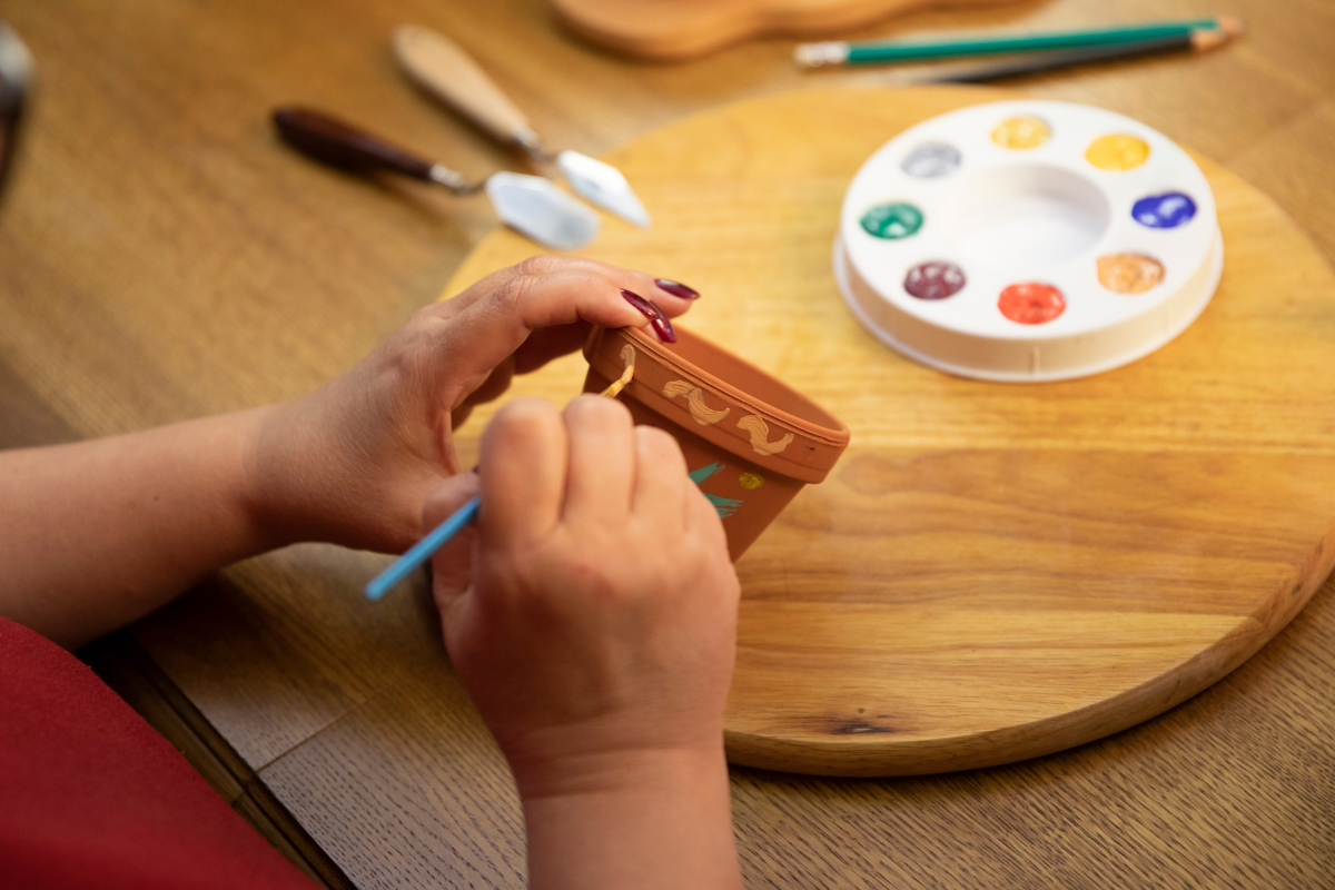 Hand-painted flower pots filled with vibrant flowers, showcasing handmade artistry.