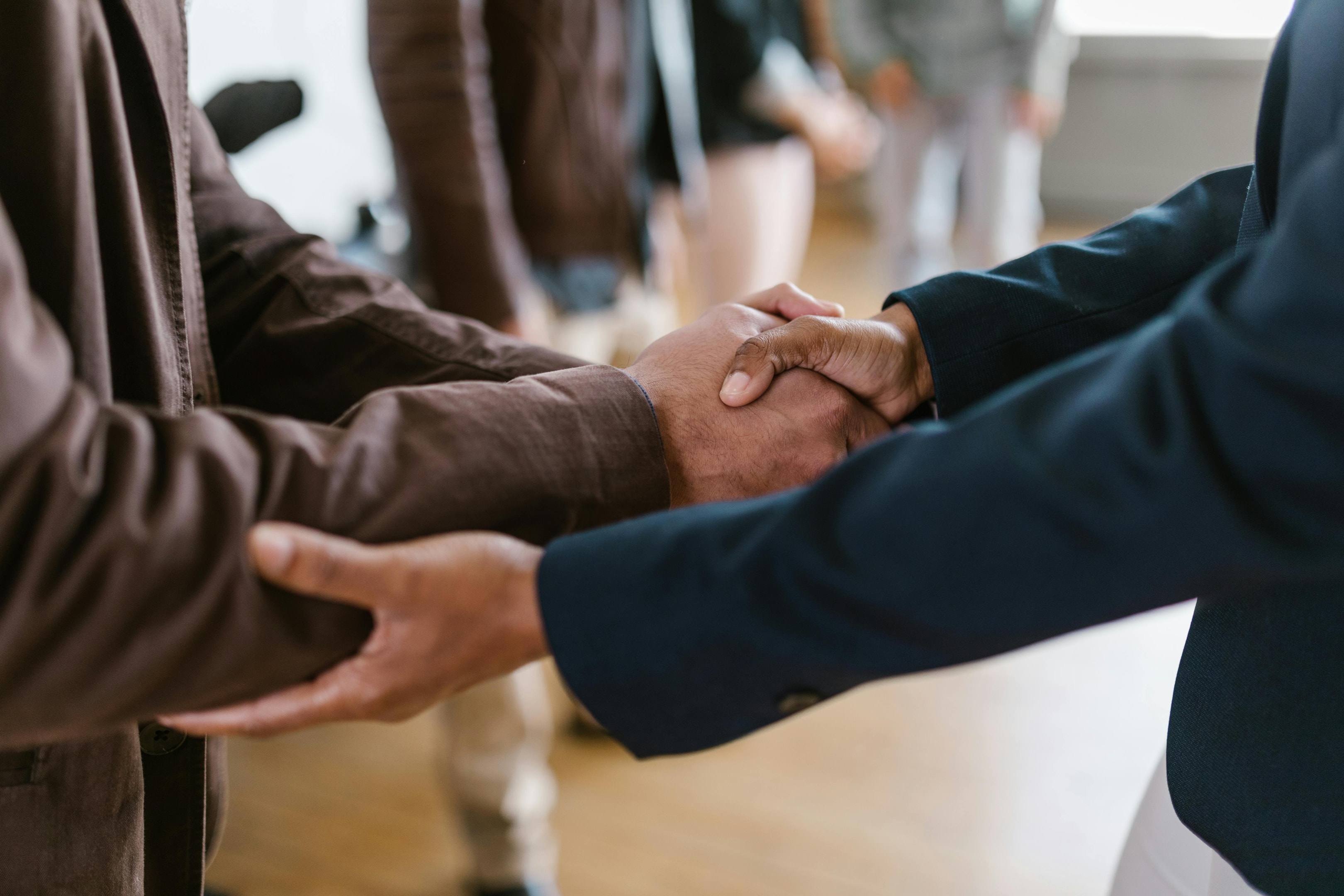 Real estate investors and wholesalers shake hands at networking event.