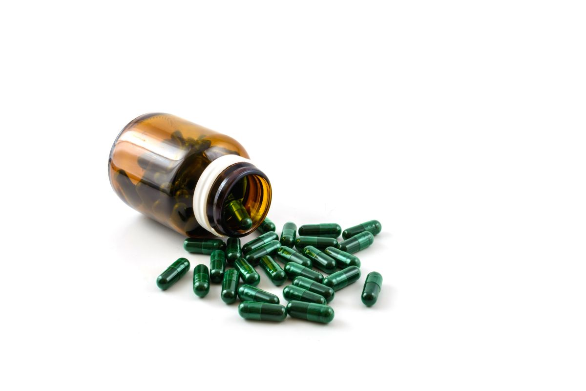 Moringa capsules after extensive food research spilling out from a bottle sold as one of the best trendy superfood used for treating health concerns like immune function, digestive system problems, HIGH CHOLESTEROL, weight loss .