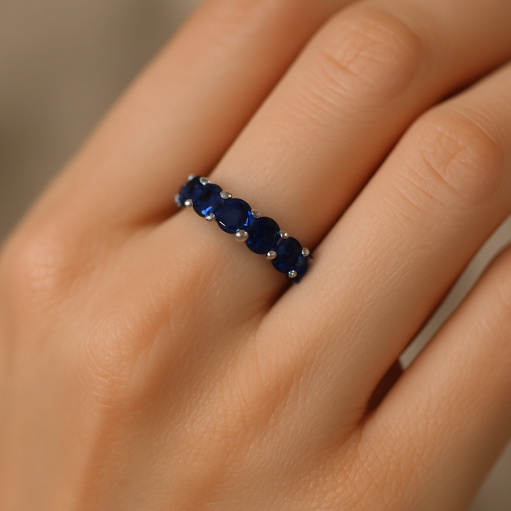 Stilingos moters ranka su elegantišku žiedu juostele iš balto aukso, puošta mėlynais safyrais ir deimantais, spindinčiais saulės šviesoje