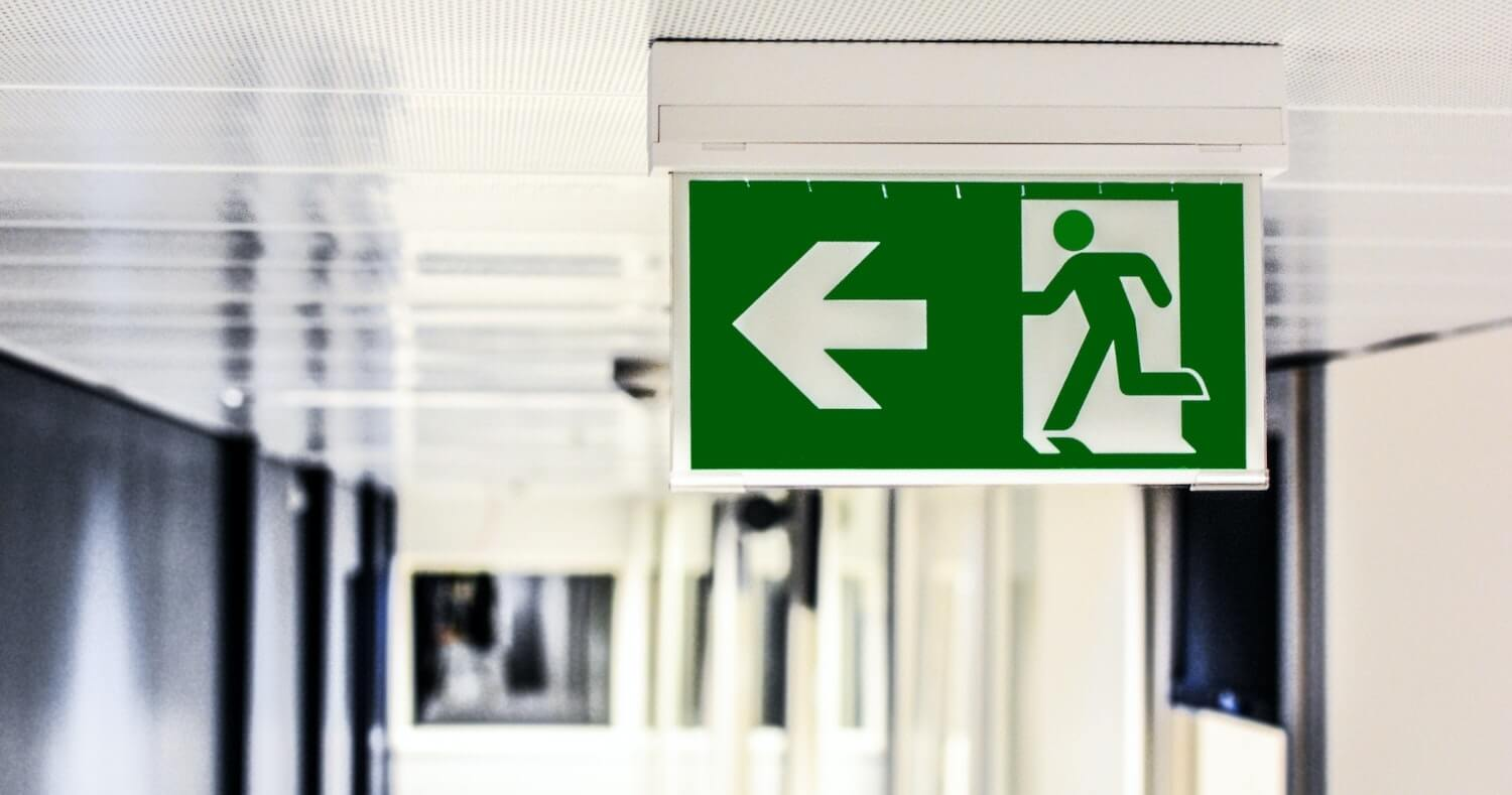 a fire exit sign on a workplace ceiling as part of emergency response planning