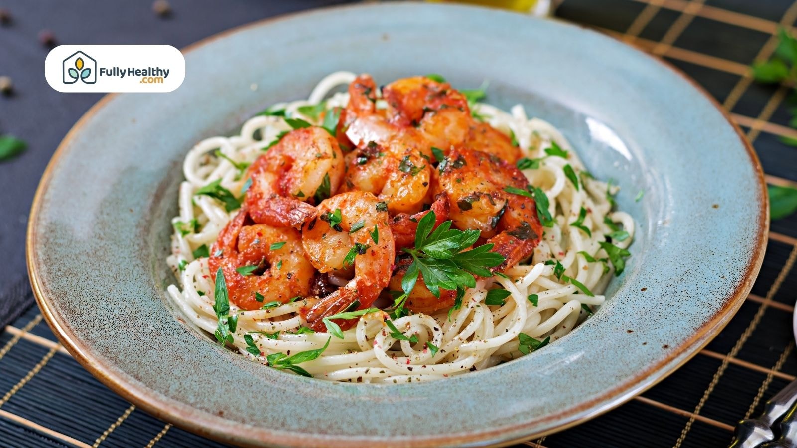 Spaghetti pasta topped with sautéed shrimp and tomato-based herb sauce in a blue ceramic bowl