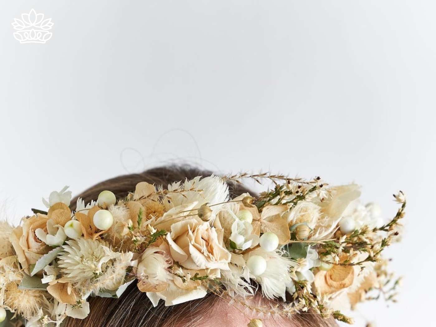 Detail of a delicate and natural-toned flower crown, featuring ivory blooms and subtle greenery, a chic and timeless headpiece from the collection at Fabulous Flowers and Gifts.