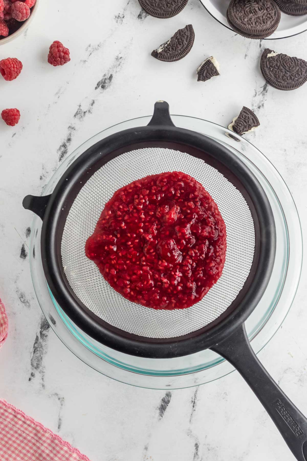 raspberry sauce in fine mesh sieve set of over large bowl