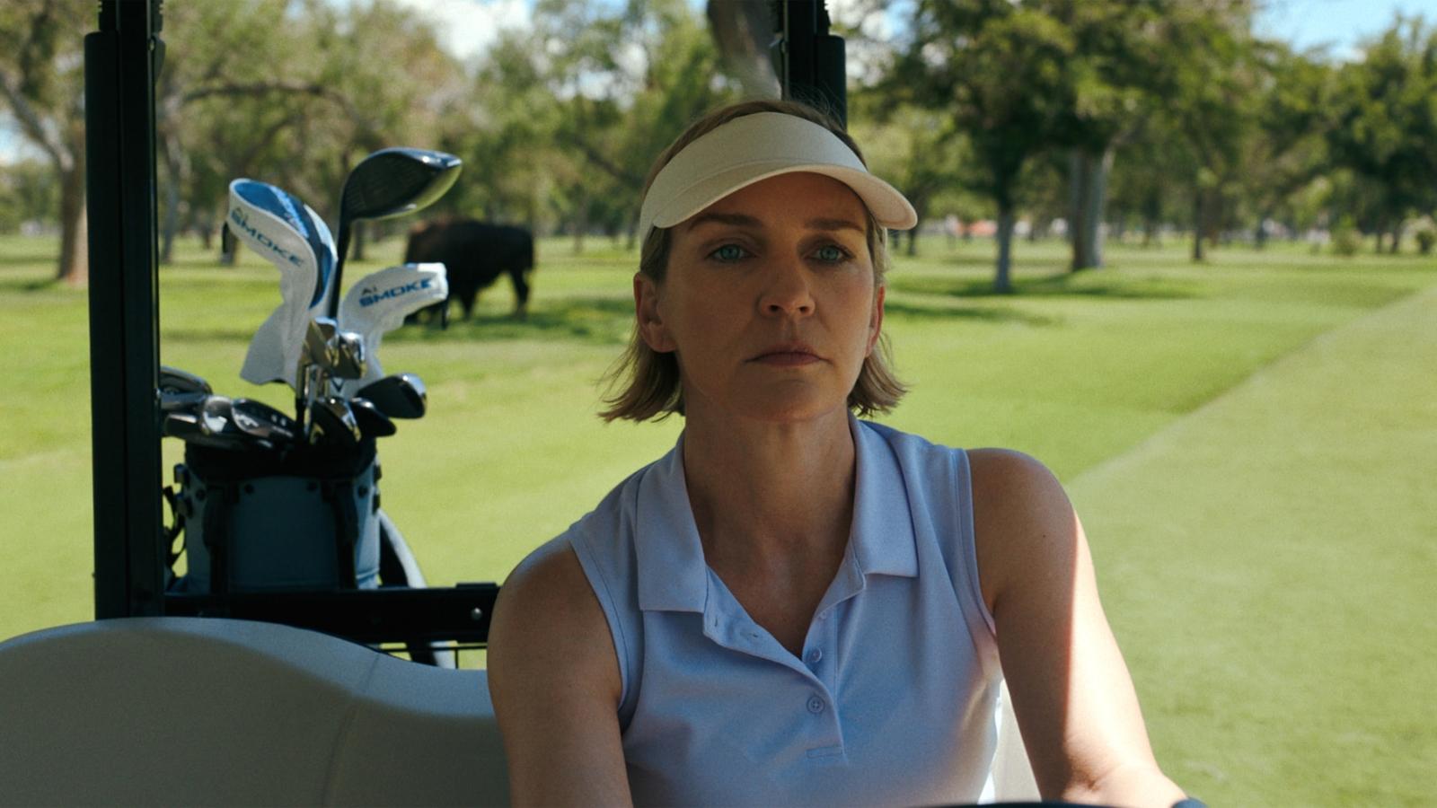 Rhea Seehorn as Carol Sturka driving a golf cart in Pluribus