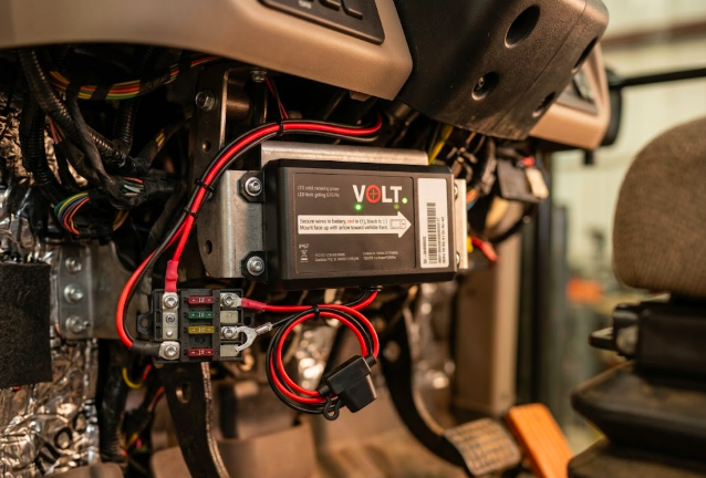 Hardwired GPS tracker installed behind tractor dashboard connected to 12V power system