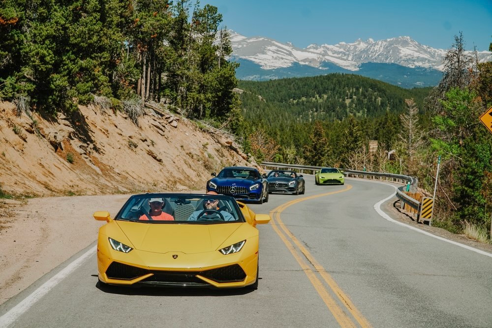 A fleet of Oxotic Supercars driving through the mountains 