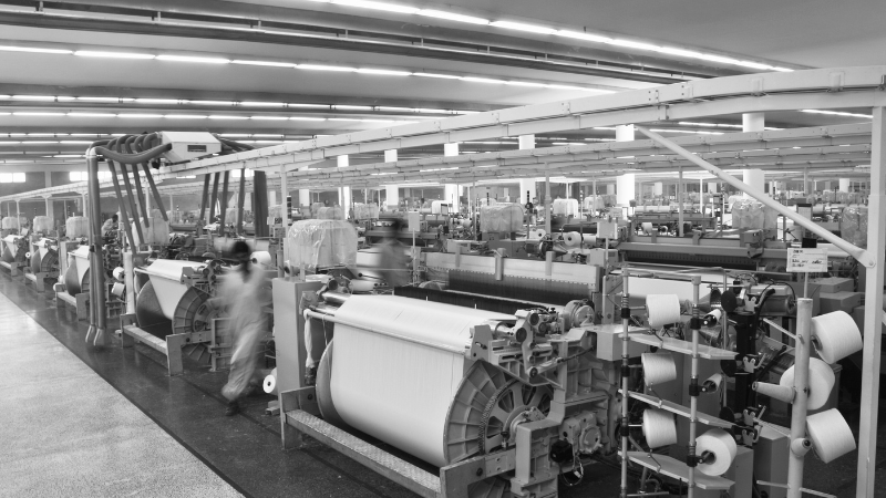 A wide shot of a textile factory with automated looms producing fabric.