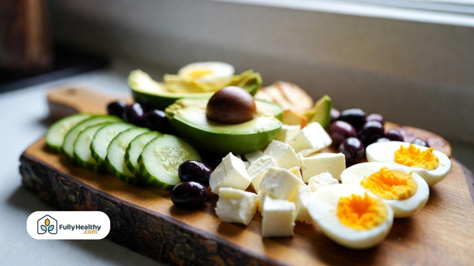Sliced cucumbers served with avocado, eggs, olives, and cheese on a snack board.