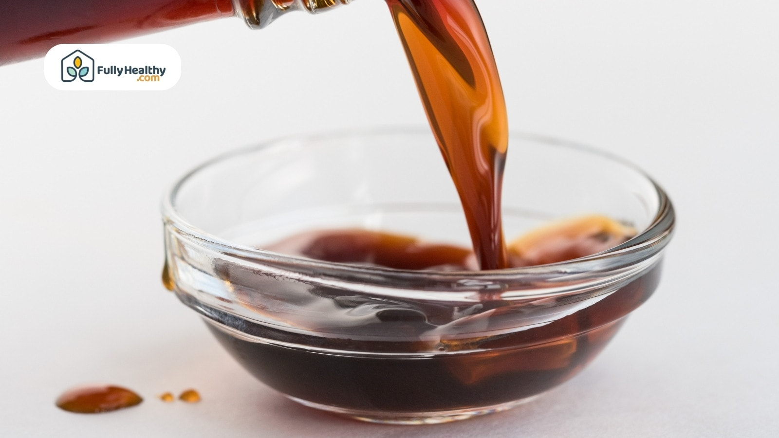 Coconut aminos being poured into small clear glass bowl close-up