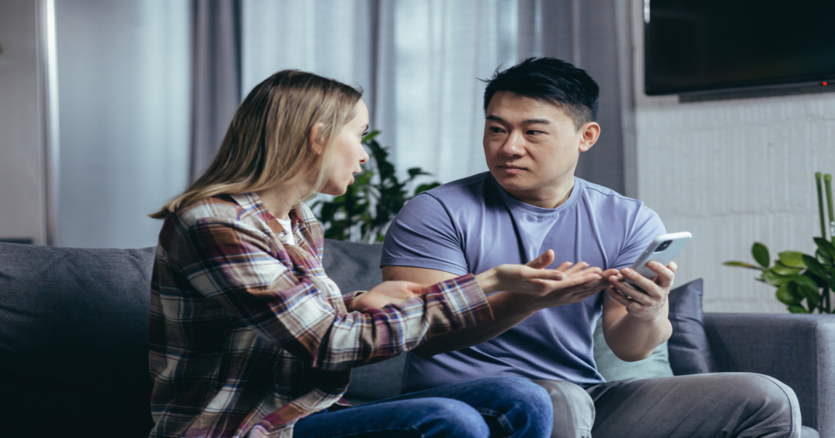  A photograph of a couple sitting on opposite sides of a couch, with their arms crossed and faces tense. The couple appears to be in the midst of a disagreement or argument. The image conveys the idea of a couple who may be in need of help to navigate conflicts in their relationship. It suggests that seeking the services of a certified Gottman Method Couples Therapist in New York City can provide the couple with the tools and techniques needed to improve their communication, build emotional connection, and reduce conflict in their relationship.