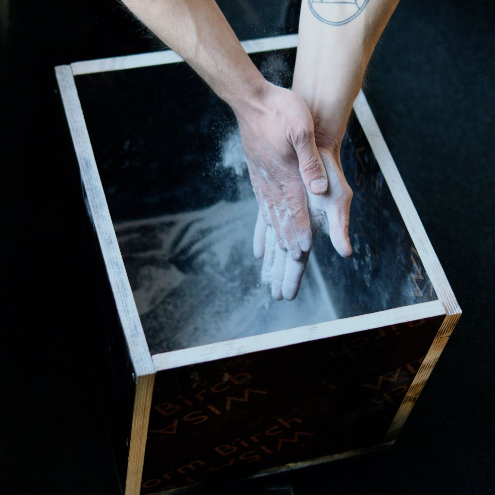 A person applying powdered chalk to their hands to improve their grip