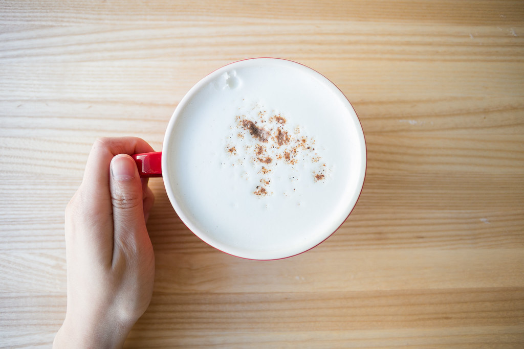 Top shot of a coffee mug with sprinkled cinnamon powder on the coffee foam.
