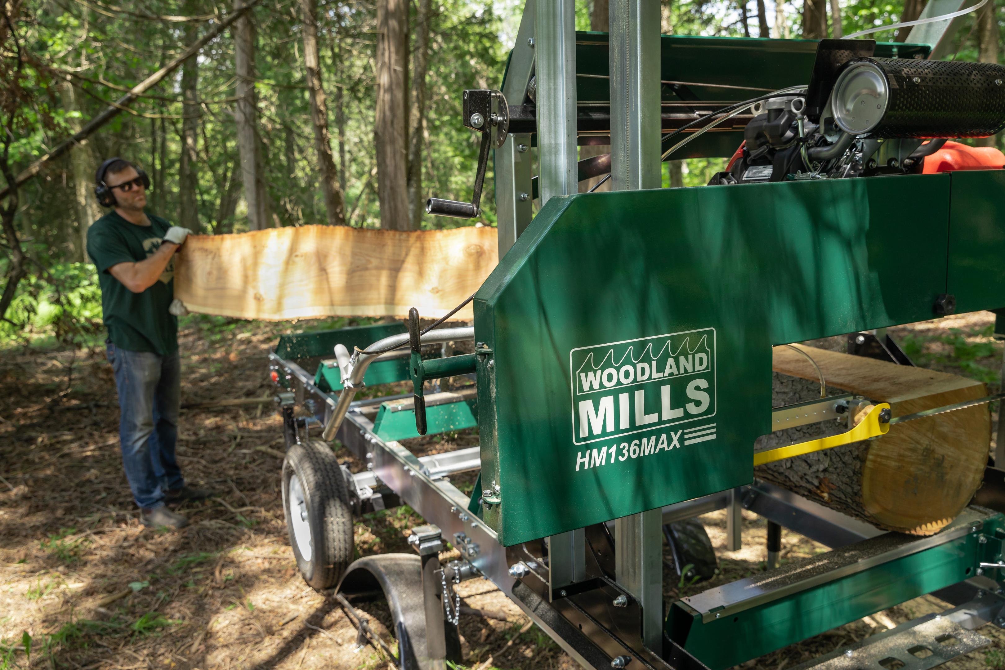 Une planche à bords naturels est retirée du rail d'une scierie mobile Woodland Mills.