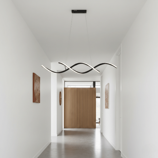 Curved linear LED pendant lighting guiding movement along a hallway ceiling.