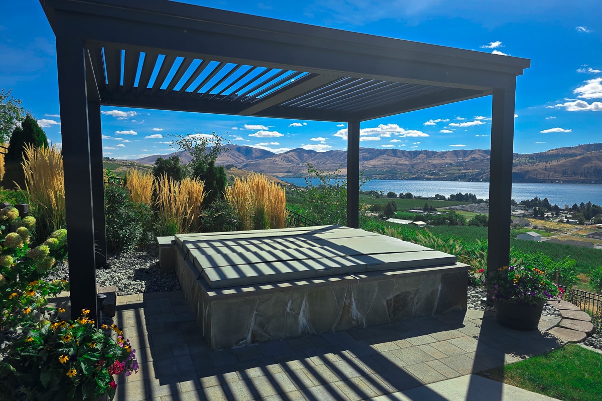 Pergola used as a hot tub cover, next to a pool and overlooking a lake.