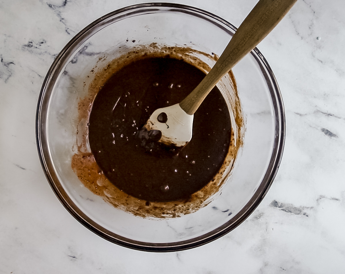 granulated sugar, cocoa, and butter in a large bowl with spatula