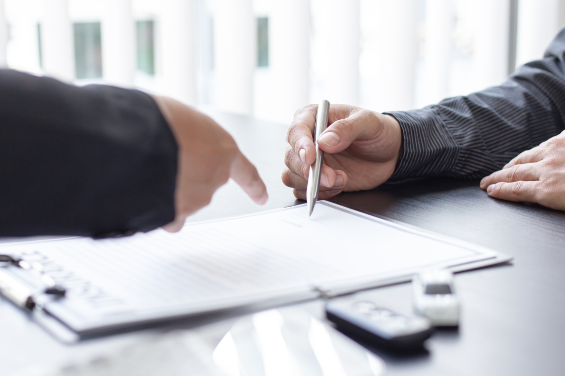 Close-up of a business broker and client reviewing and signing a sales contract during a business transaction