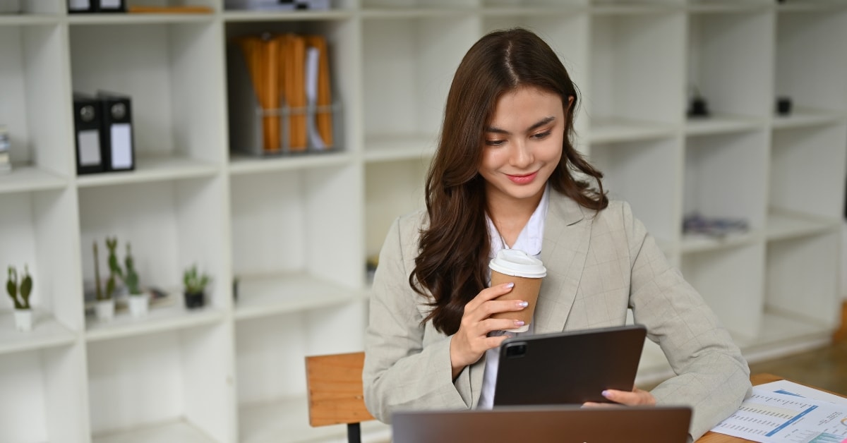 Professional woman with tablet and coffee, reviewing her unfiled tax returns for OnlyFans income.