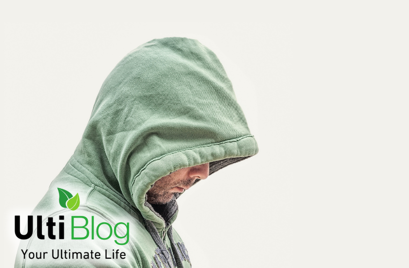 Man covering face with a hoodie. His face is looking down in post about Is Smoking Weed A Sin?