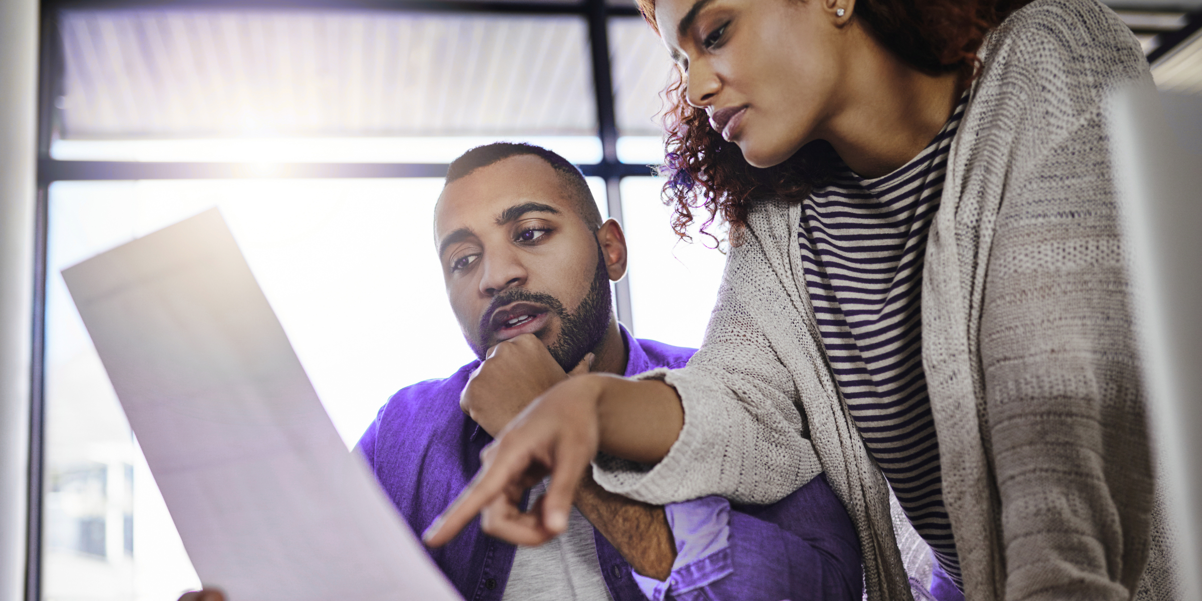 Two employees reviewing a document together in a bright office, illustrating remote team communication policies and effective communication practices.
