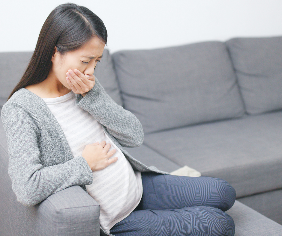 A person holding their stomach in discomfort, experiencing stomach pain after quitting alcohol as an early stage symptom.