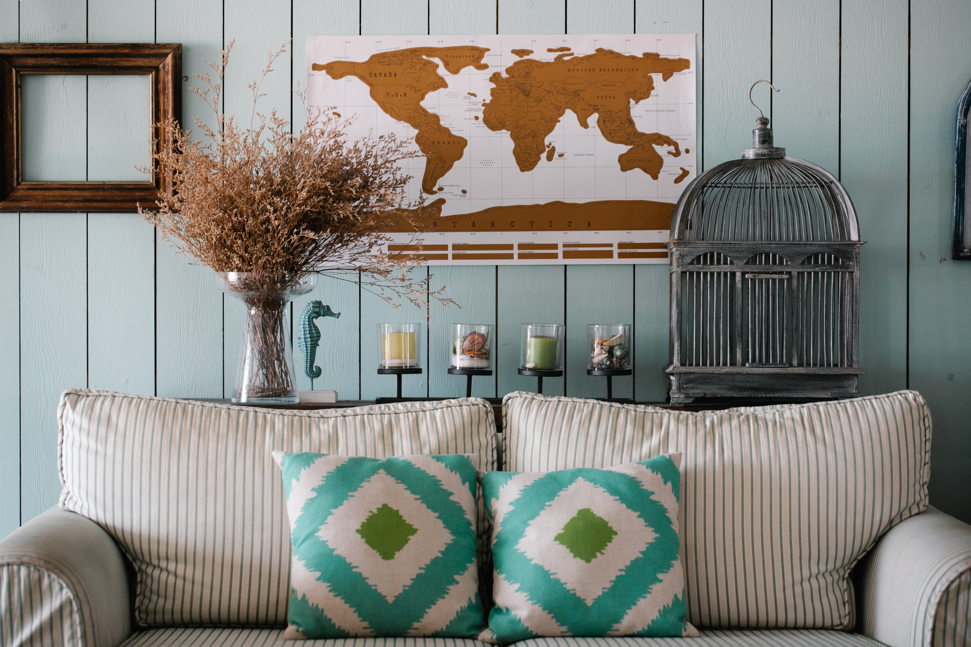 white and green striped sofa with bird cage and wall map decor