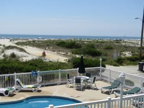 The image showcases a stunning oceanfront view of the Ocean Sands property from the spacious pool area. This picturesque setting highlights the breathtaking ocean views and modern amenities, inviting guests to unwind and enjoy their stay in Wildwood, New Jersey.