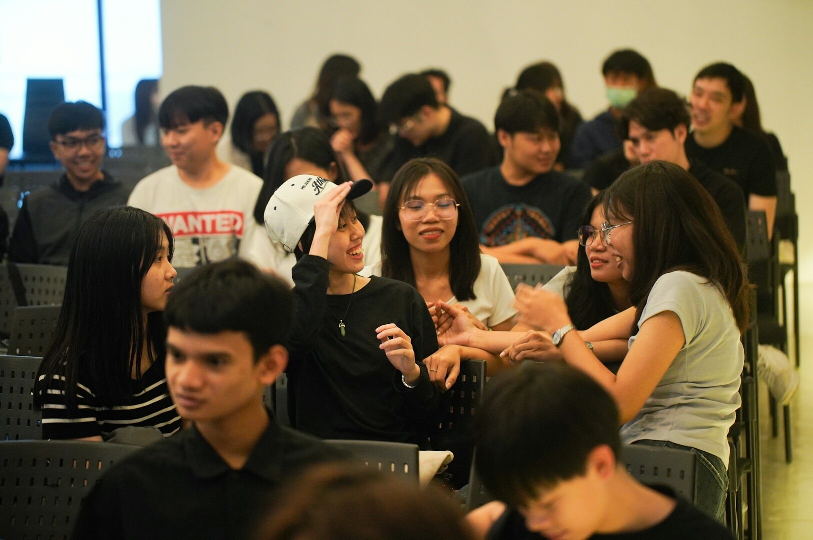  Several Singaporean international students sitting in chairs, participating in a collaborative discussion in a room.
