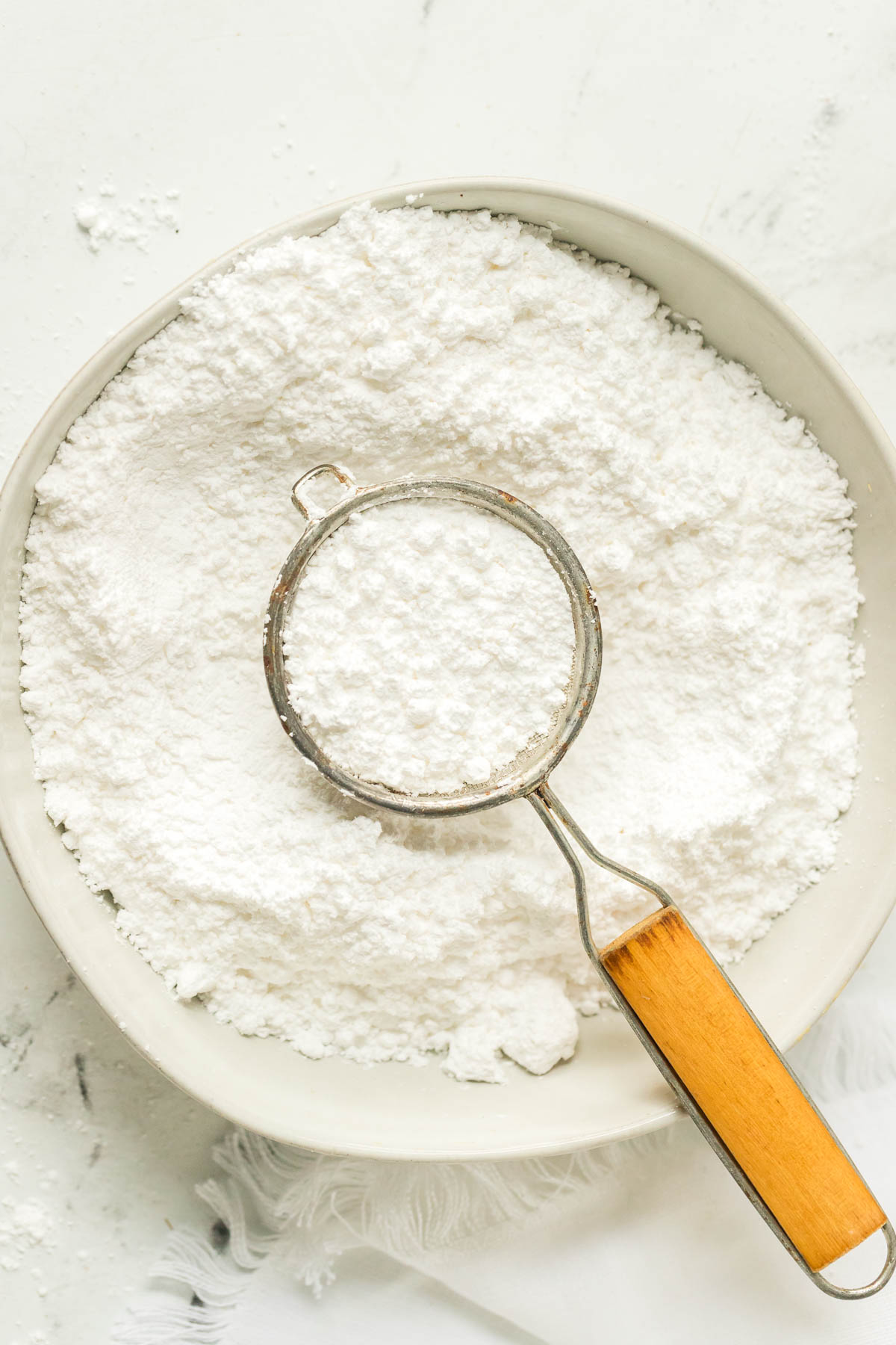 bowl of powdered sugar with a sifter in it