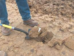 A picture of a person using a shovel to loosen compacted soil