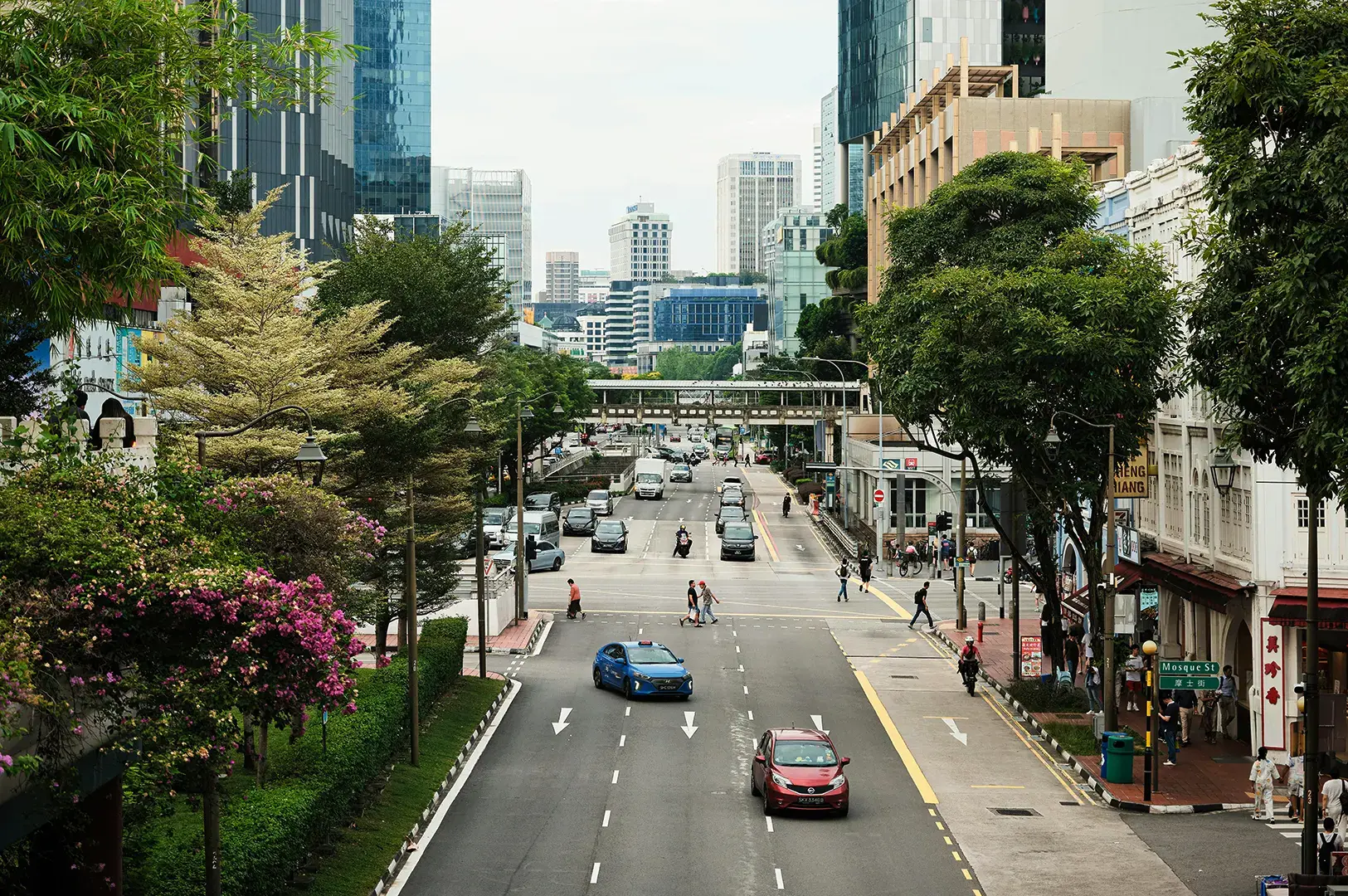 Multi-lane road with overhead bridge and city skyline.