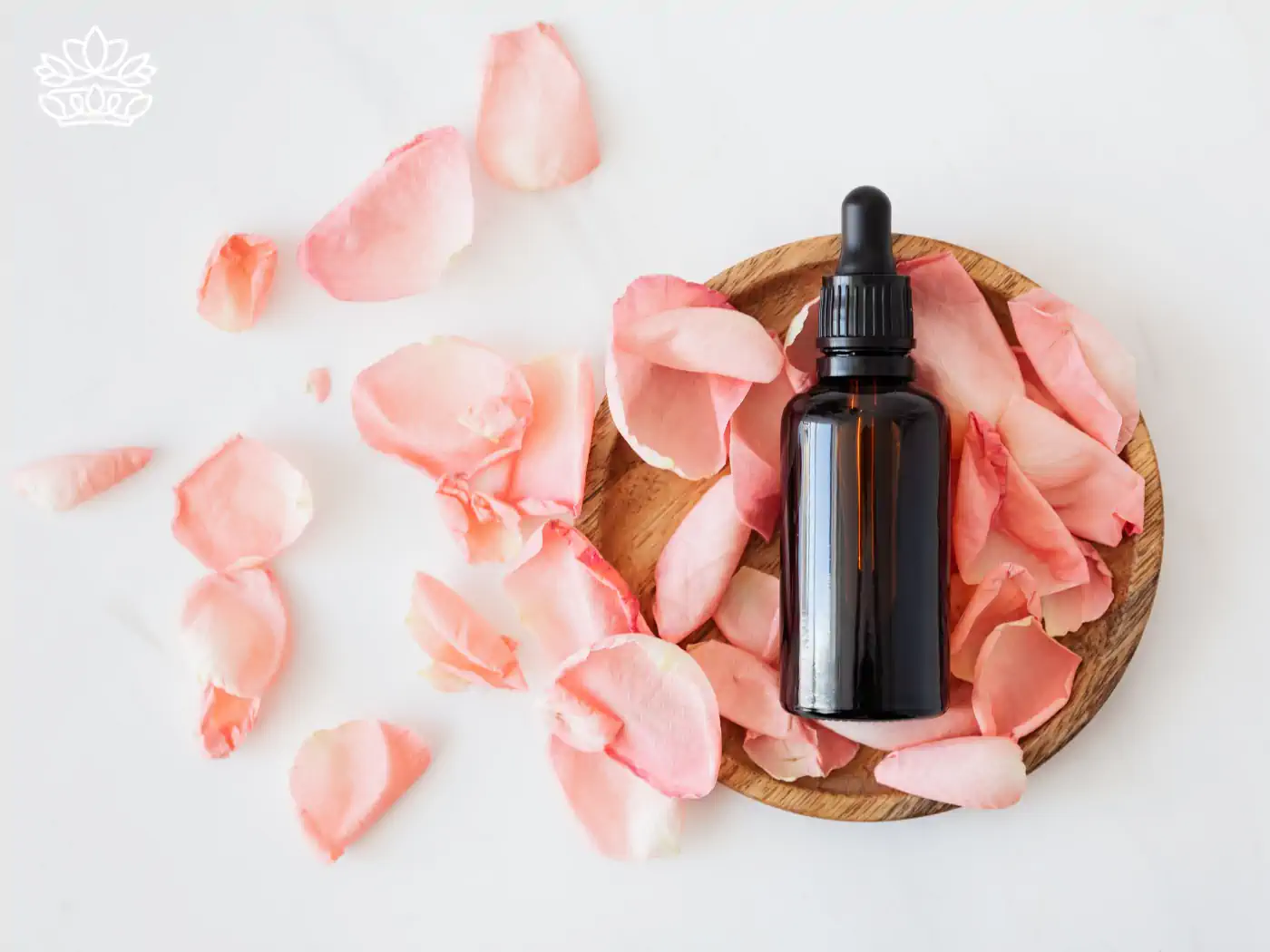 Essential oil bottle on a wooden dish with pink rose petals. Collection: Essential Oils, Fabulous Flowers & Gifts.
