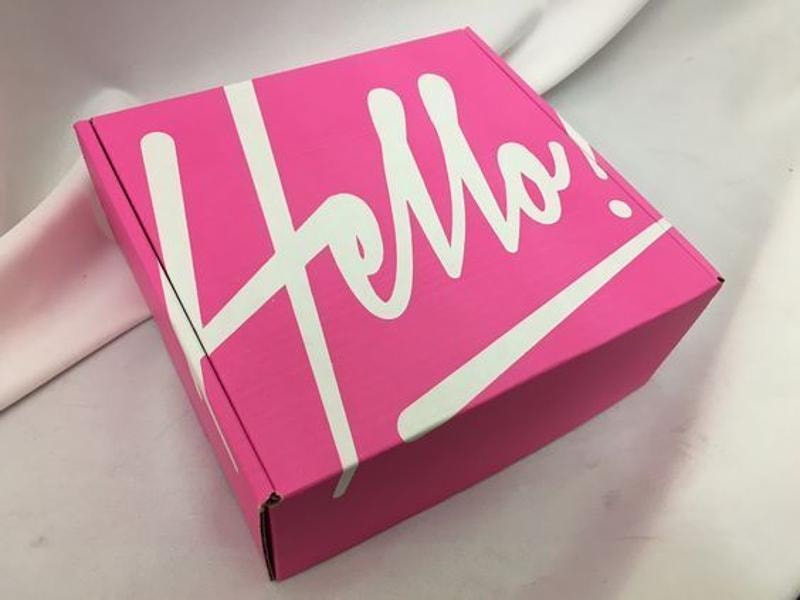 A picture of a bright pink box with the word “hello!” written in white on the lid.