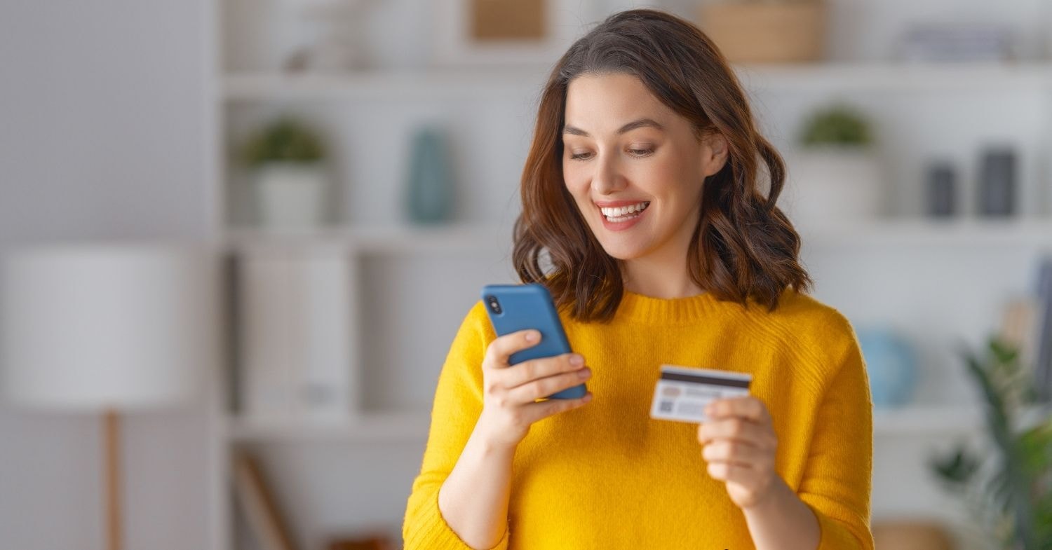 Woman holding a phone and credit card, preparing to pay excise tax online efficiently.