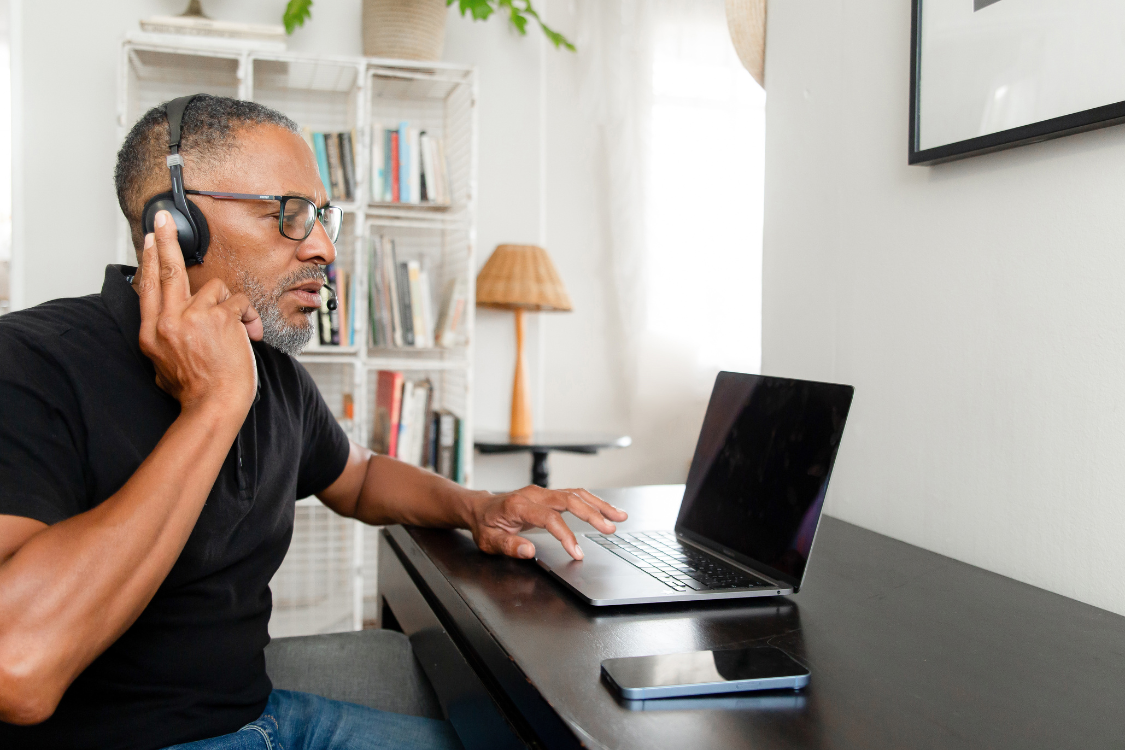Remote worker managing tasks from home with headset and laptop