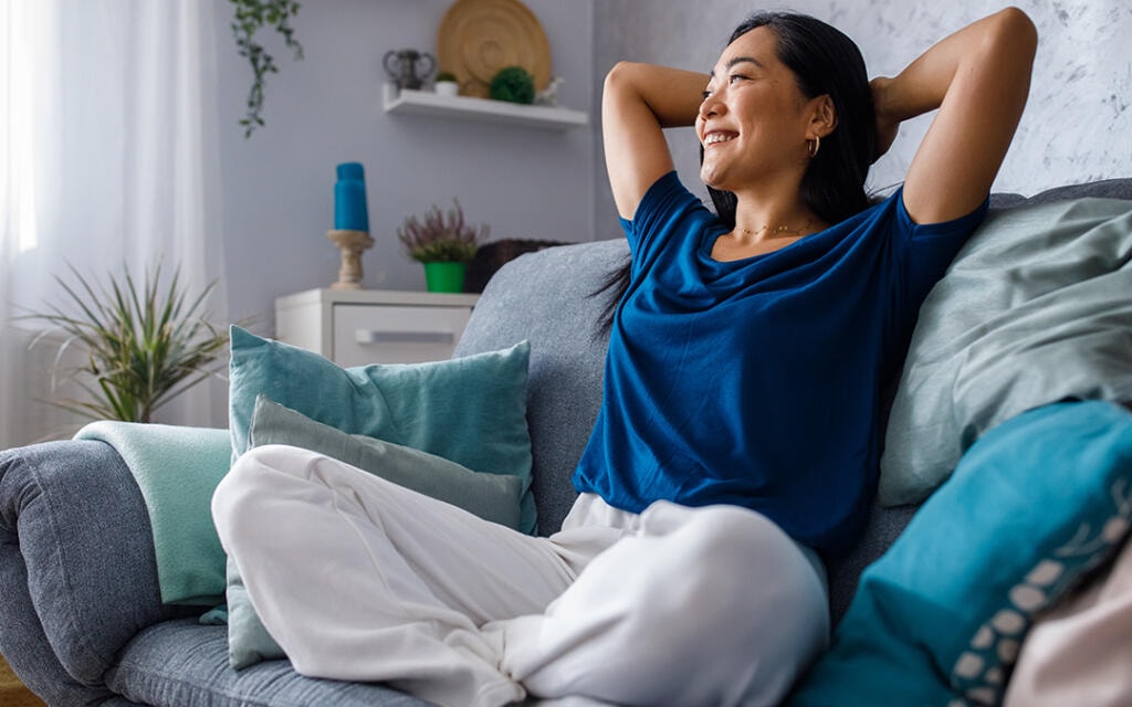 Woman relaxing on a couch at home after rehabilitation post surgery, showing comfort and steady progress during recovery.