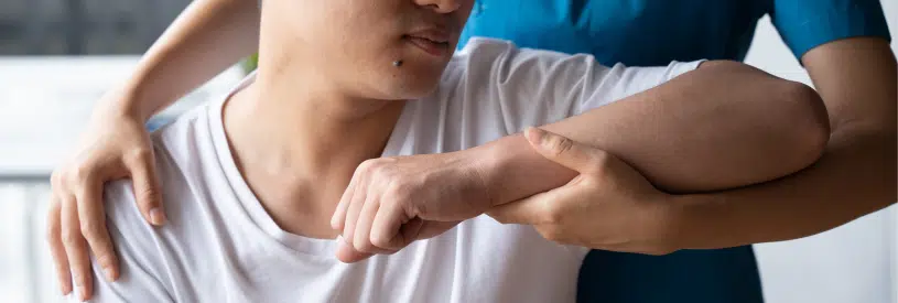 Clinician guiding a patient’s arm during a shoulder mobility assessment.