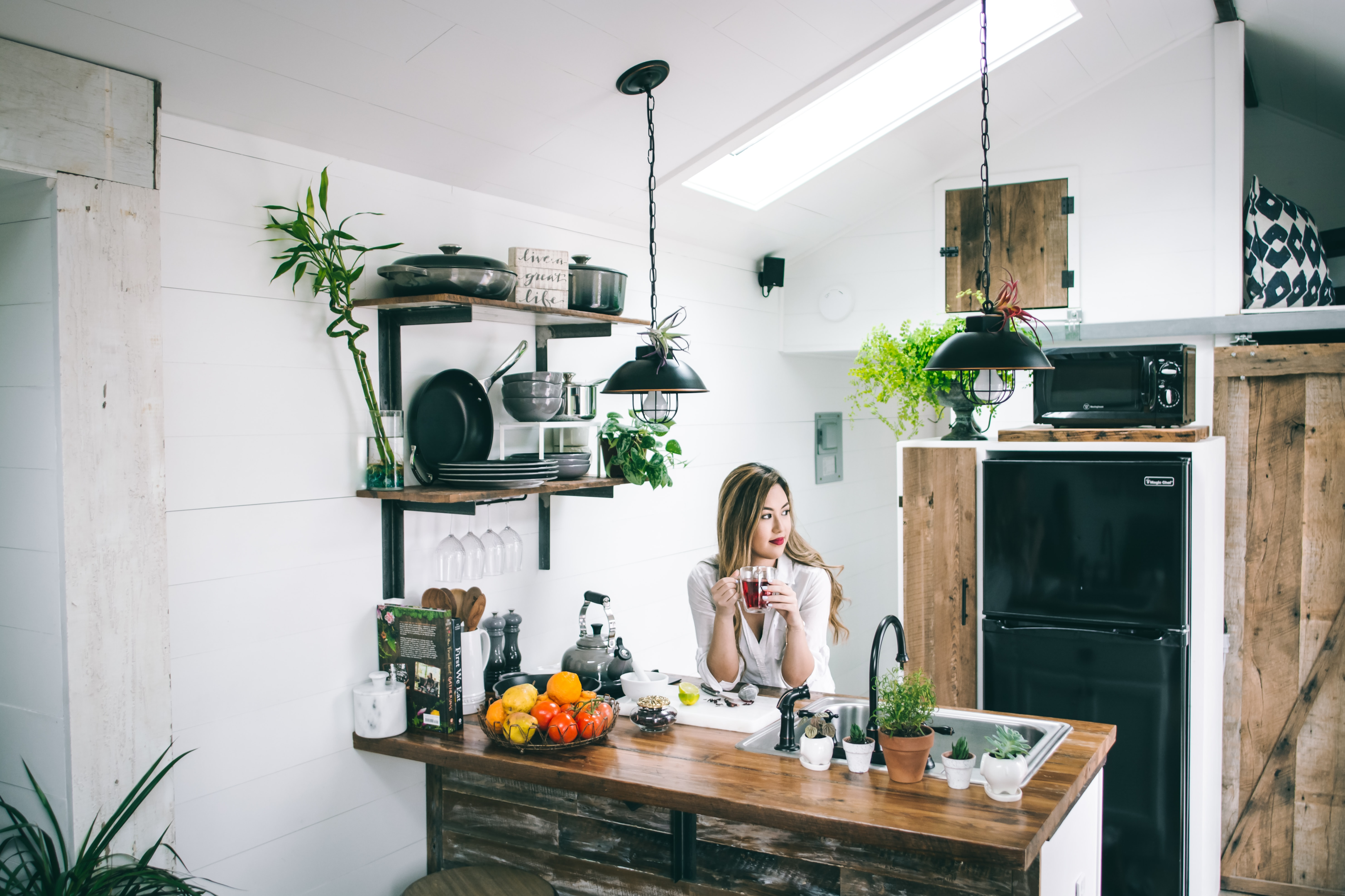 Photo of a girl standing beside her kitchen countertop while holding a cup of coffee