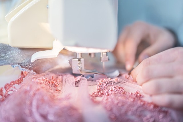 dressmaker working on a pink beadded custom design for clients focusing on the details using the proper materials for the project before getting her pay
