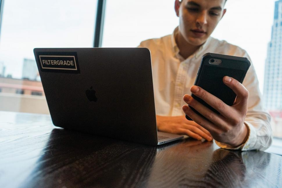 Person checking his phone while using laptop